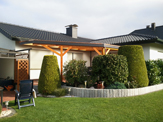 Terrassen-Überdachung aus BSH Holz mit einer Schieferblende, Kupfer-Kante und einer Doppelstegplatten Dacheindeckung – in Lage/Lippe